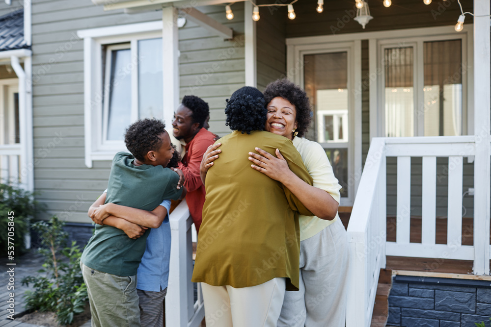 Wall mural Big African American family embracing outdoors welcoming guests for housewarming party