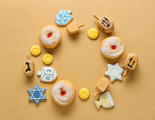 Fototapeta na wymiar Frame made of dreidels, cookies and donuts for Hanukkah celebration on color background