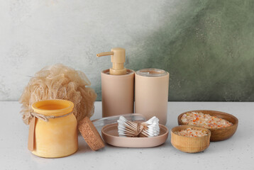 Bath accessories with bowls of sea salt on table near color wall