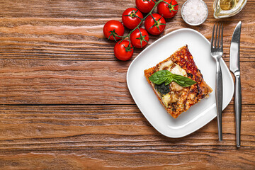 Plate with piece of tasty Italian pie on wooden background