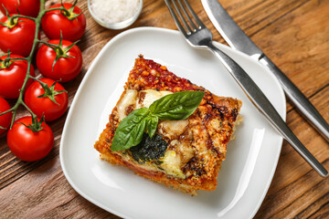 Plate with tasty Italian pie with mozzarella and pesto sauce on wooden background, closeup
