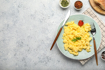 Plate of tasty scrambled eggs and spices on light background