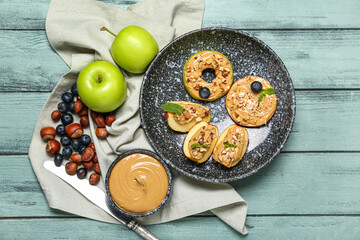 Composition with tasty apple wedges, nut butter, blueberry and hazelnuts on color wooden background