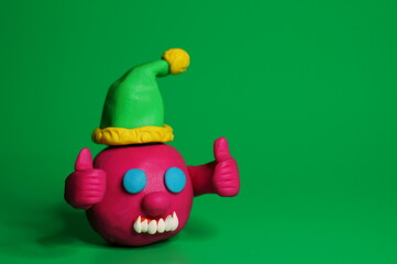 Fototapeta premium A virus figurine in a festive hat with thumbs up. Green background. Christmas toys.