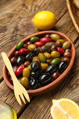 Plate with different kinds of delicious olives on wooden background, closeup