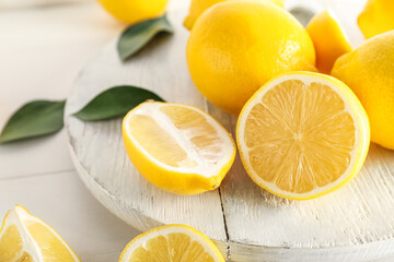 Wooden board with fresh lemons on table, closeup