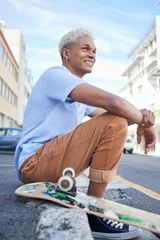Tuinposter Relax, skateboard and city black man in street of California in summer with Gen Z fashion. Edgy, young and trendy African American skater male in the USA resting on urban road with smile. © Wesley J/peopleimages.com