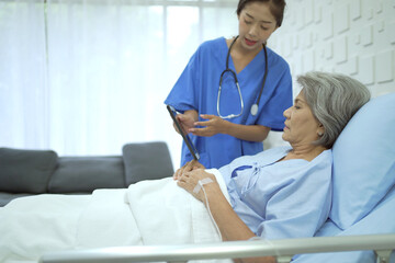 Specialist doctor or professional physician visiting a senior female patient in recovery ward hospital in hospital.