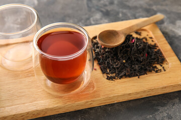 Wooden board with cup of black tea on dark background, closeup