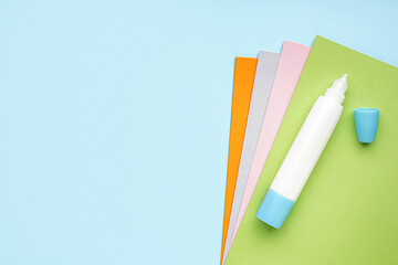 Stationery glue with paper sheets on blue background