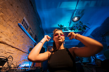 Beautiful female DJ dancing to techno in a small club