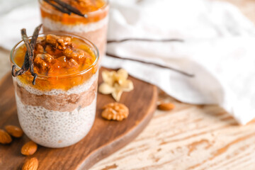 Glass of tasty chia seed pudding with jam on wooden table
