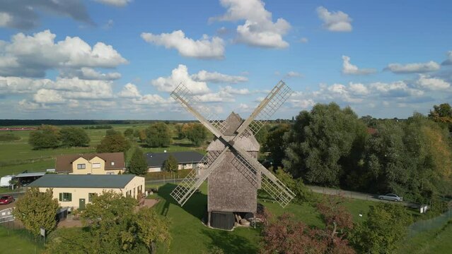 Flat green land, historic buildings. Dramatic aerial view flight panorama orbit drone
of a old Trestle windmill in brandenburg Germany at summer golden hour 2022. 4k marnitz Cinematic