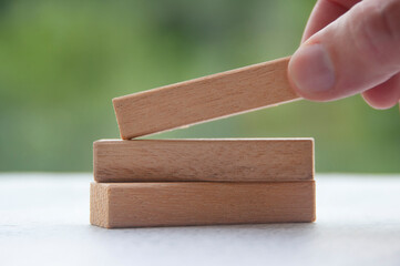 Hand lifting one wooden block with customizable space for text or ideas. Copy space
