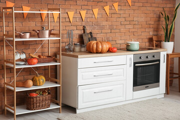 Interior of modern kitchen with Halloween pumpkins, counters and shelving unit
