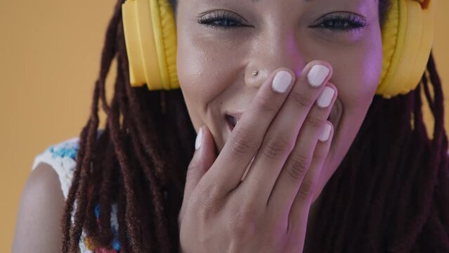 Beautiful jamaican woman with dreadlocks portrait and face expressions set in studio. Latin american woman dancing and making party over a yellow background