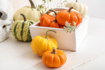 Basket with Halloween pumpkins on light wooden background