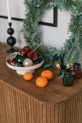 Tangerines, Christmas decor, wreath on wooden dresser. Modern home holiday decorations.