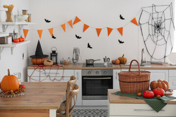 Interior of modern kitchen decorated for Halloween with pumpkins and counters