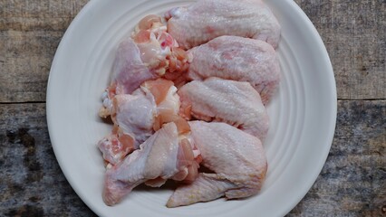 Fresh chicken wings and chicken drumsticks on a white plate 