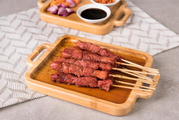 Pork satay with char siu seasoning served with chopped chili, chopped onion, tomato and sweet soy sauce
