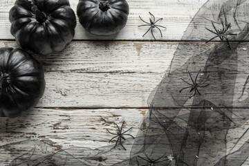 Black Halloween pumpkins and veil on light wooden background