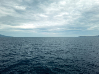 Sea dark blue ripple water meets cloudy sky background. Greek island, Cyclades, Greece. Space