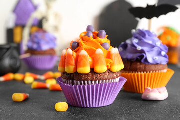 Tasty Halloween cupcakes with candy corns on dark table, closeup
