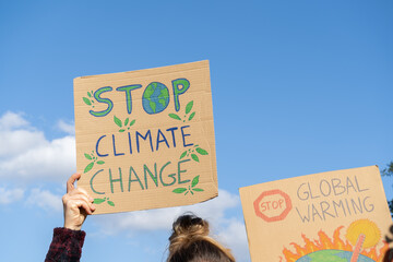 Protesters holding signs with slogans Stop Climate Change and Stop Global Warming. People with placards at protest rally demonstration strike.