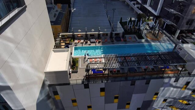 aerial footage of a pool and a lounge area surrounded by lush green trees and plants on the side of a skyscraper in downtown Atlanta Georgia USA