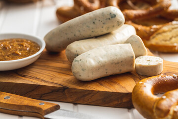 Traditional Bavarian white sausages on cutting board and pretzels.