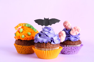 Tasty Halloween cupcakes on pink background