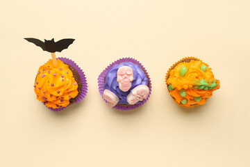 Tasty Halloween cupcakes on beige background