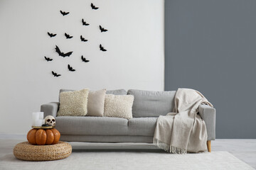 Interior of light living room decorated for Halloween with sofa and pouf