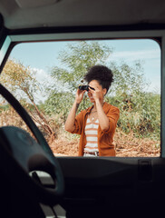 Road trip, travel and binoculars with a sightseeing woman outdoor in nature for a summer vacation...