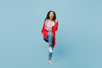 Fototapeta na wymiar Full body excited happy fun young woman of African American ethnicity 20s she wears red jacket do winner gesture isolated on plain pastel light blue cyan background. Wet fall weather season concept.