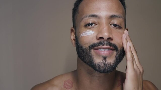Handsome man taking care of his skin with beauty natural products and treatments. Latin american male posing on a background in studio. Beauty lighting set up and close up angles