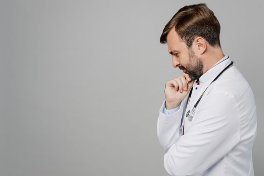 Sideways Pensive Minded Male Doctor Man Wearing White Medical Gown Suit Stethoscope Work In Hospital Prop Up Chin Isolated On Plain Grey Color Background Studio Portrait. Healthcare Medicine Concept.