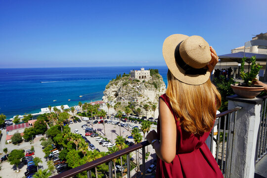 Tourism in Italy. Rear view of beautiful fashion girl enjoying view of Tropea village on the Coast of the Gods, Calabria. Summer vacation in Europe.