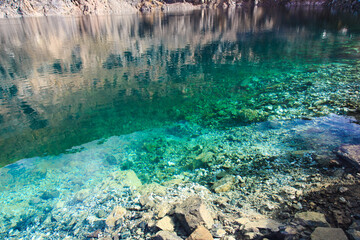 Texture of emerald clear water and natural stones. Natural background. Blue Lake.