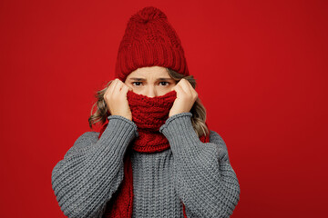 Young sad tired woman wearig warm gray sweater hat cover mouth with scarf feel bad isolated on...