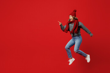 Full body side view young woman wear grey sweater scarf hat jump high run hurry up isolated on plain red background studio portrait. Healthy lifestyle ill sick disease treatment cold season concept.
