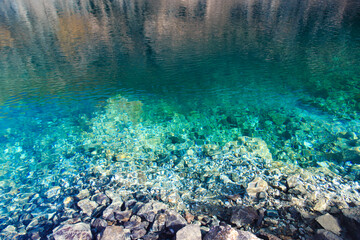 Texture of emerald clear water and natural stones. Natural background. Blue Lake.