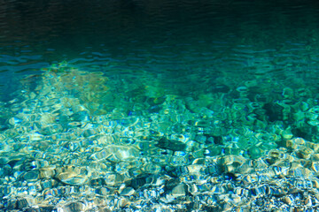 Texture of emerald clear water and natural stones. Natural background. Blue Lake.