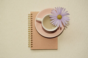 Pink cup of coffee and notebook on desk. top view