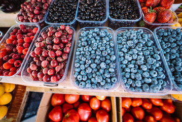Blueberries and gooseberries on counter of farm market for sale.