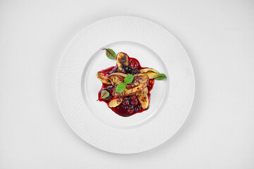 Foie gras with berry sauce on a white plate on a white plate. Close-up. Selective focus