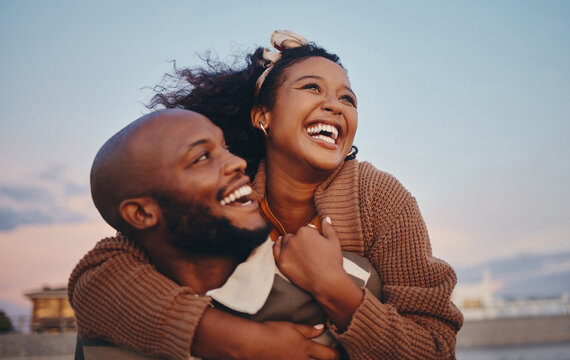 Happy black couple, love and hug laughing in joyful happiness for bonding time together in the outdoors. African American man and woman enjoying playful fun piggyback with smile for holiday in nature