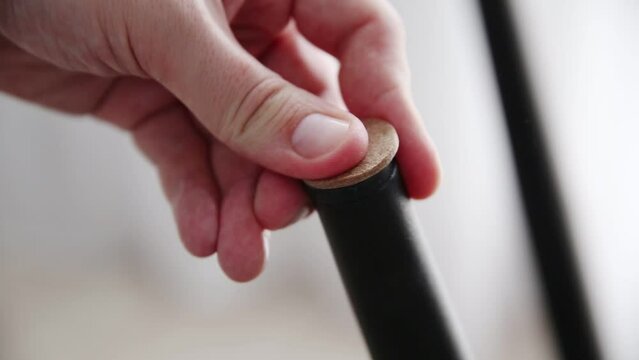 A man glues protective pads on the legs of a chair. Protection against floor scratches and noise, close-up