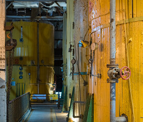 the interior of an abandoned factory with pipes and rusty metal structures